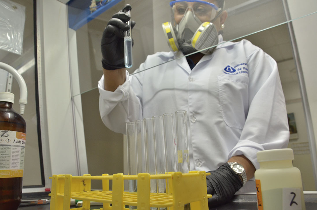Imagen de estudiante en el laboratorio del programa de Biología Ambiental de la Universidad de Ibagué sostiene en su mano derecha una probeta